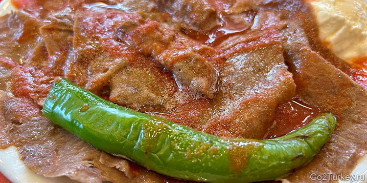 Искендер-кебаб - это тонкие ломтики мяса на горячем пиде, политые томатным соусом и йогуртом, изысканное и ароматное блюдо, идеально подходящее для зимнего отдыха